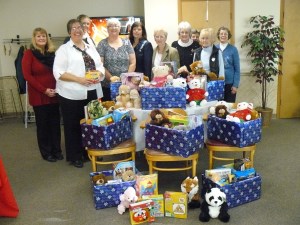 DAR members behind boxes filled with books and Teddy Bears wrapped in Christmas paper.